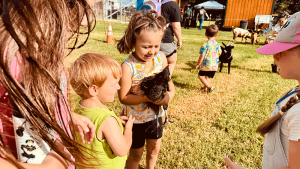 Child visiting our farm and petting a chicken.
